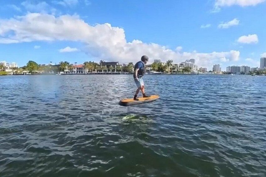 Une personne fait de la planche à rame sur une étendue d’eau calme, avec la silhouette d’une ville en arrière-plan. 4
