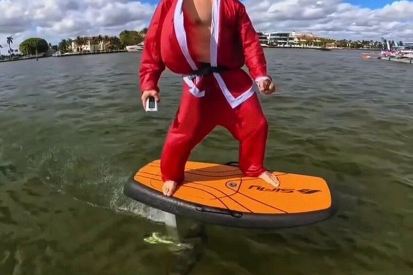 Une personne vêtue de rouge, debout sur une planche de surf dans l’eau. 2