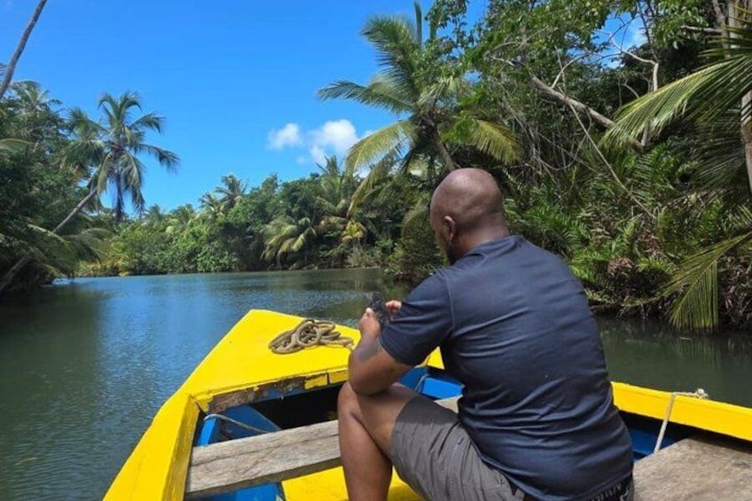A man in a boat on a river surrounded by dense tropical vegetation. 5