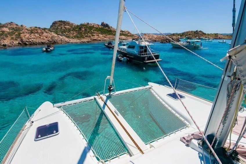 A boat deck with a view of turquoise waters and several boats anchored nearby. 3