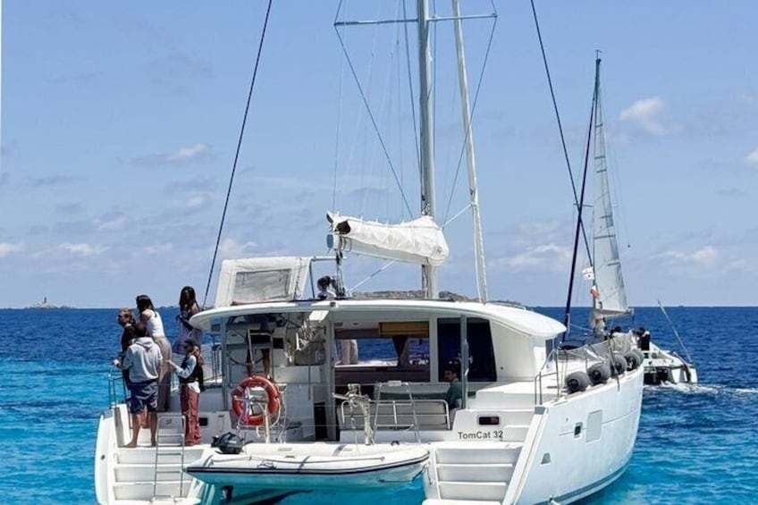 A white yacht named TomCat32 with people on deck and another sailboat in the background. 1