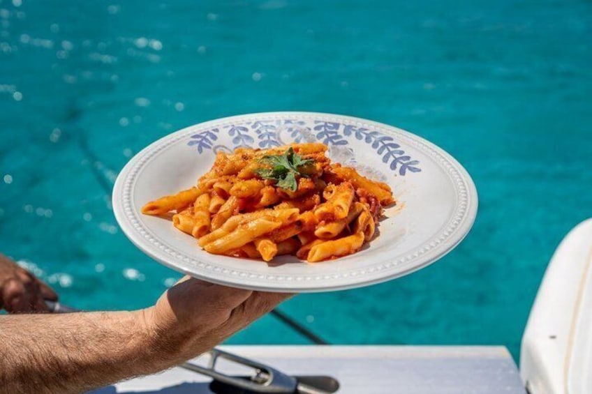 A plate of pasta with a blue pattern, held over a pool. 2