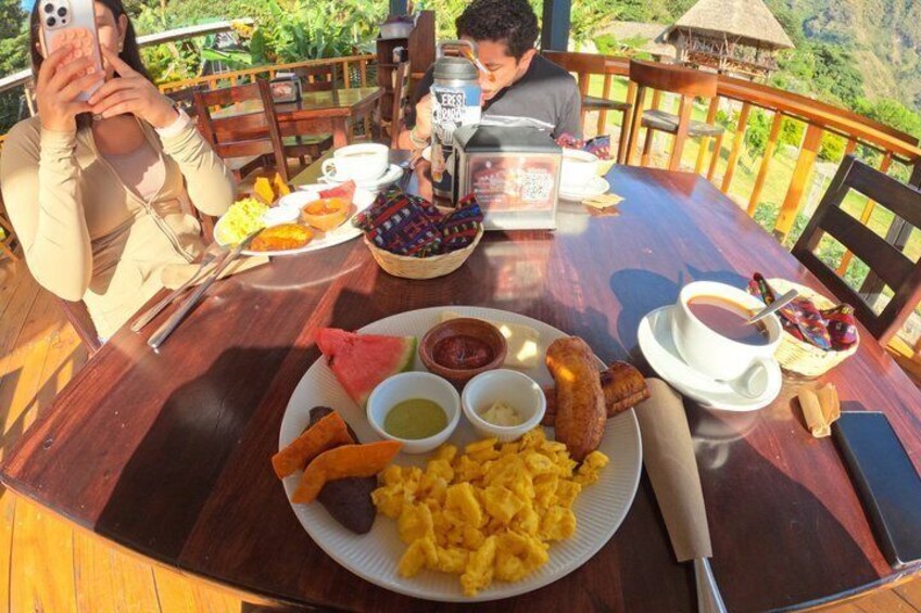 A wooden dining table with a plate of food, a cup of coffee, and a smartphone. 3