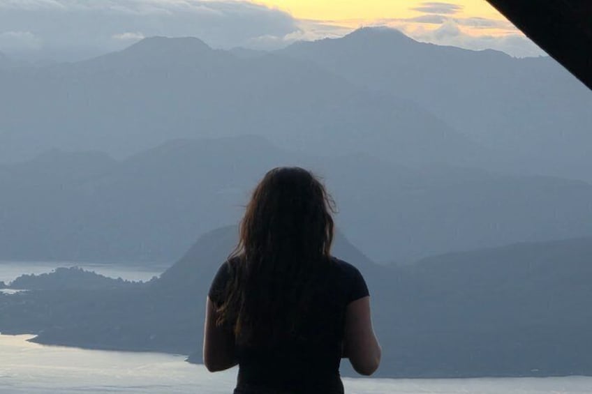 A person standing with a view of mountains and a body of water. 5