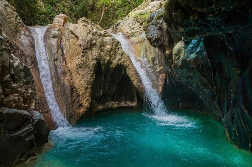 Une cascade se jetant dans une piscine aux eaux turquoise, le tout entouré d'un paysage rocheux. 2