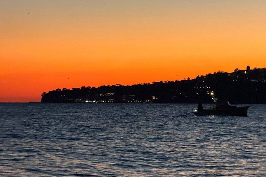 A sunset over a coastal town with a boat on the water. 5