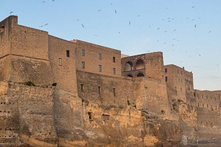 A large, ancient stone fortress with multiple levels and arched windows, surrounded by a high wall. 2