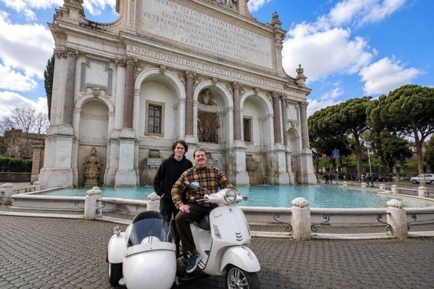 A historic fountain with inscriptions, a paved area, and a clear sky. 3