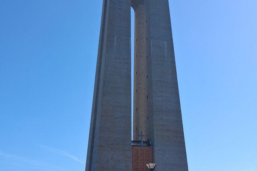 Una estructura alta y estrecha de hormigón con un extremo puntiagudo contra un cielo azul despejado. 4