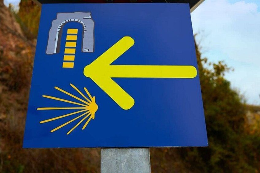 A directional sign with a yellow arrow and symbols indicating a path or trail. 4