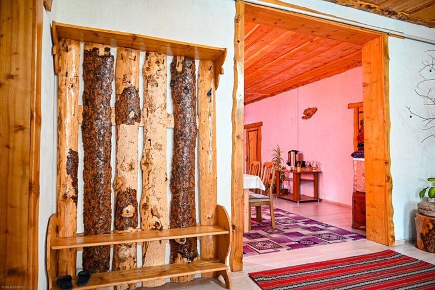 Un intérieur rustique avec un banc en bois, un mur rose et un coin repas agrémenté d’un tapis violet. 3