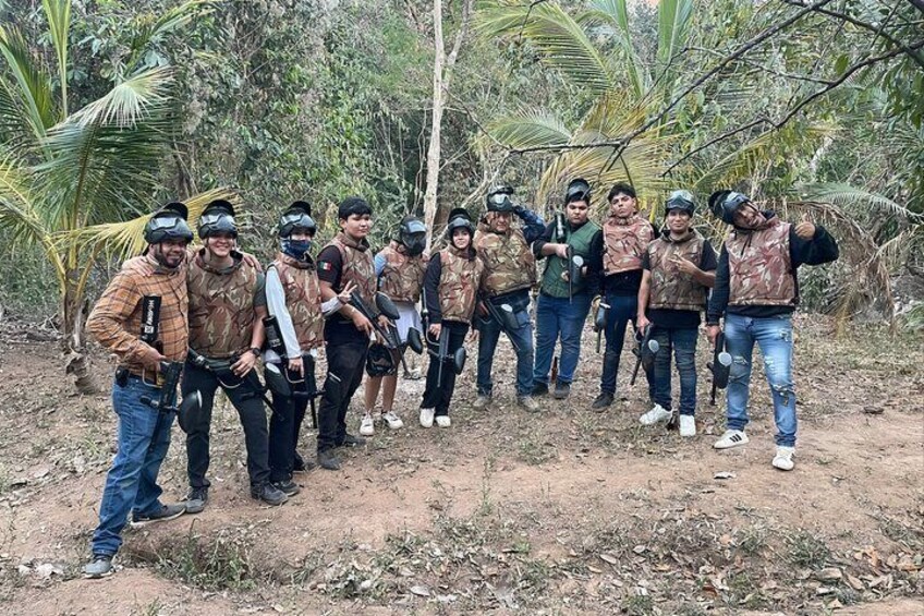 A group of people in camouflage vests and helmets standing in a forested area. 1