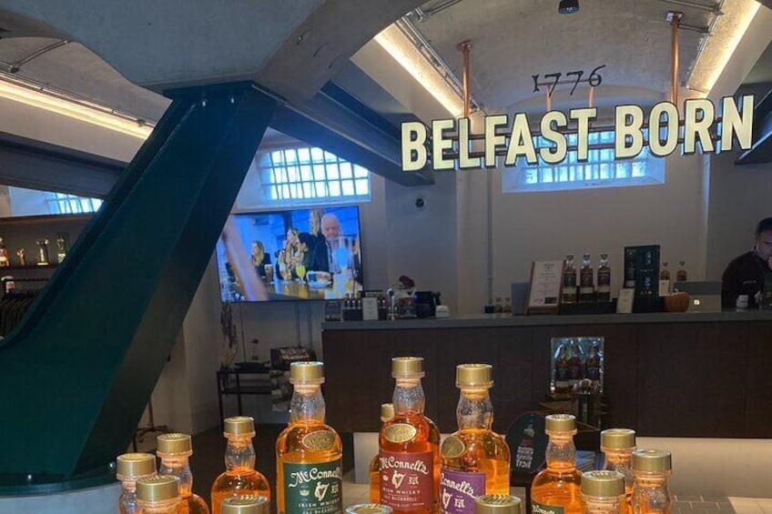 A bar with a counter, bottles of liquor, and a sign reading "BELFAST BORN". 1