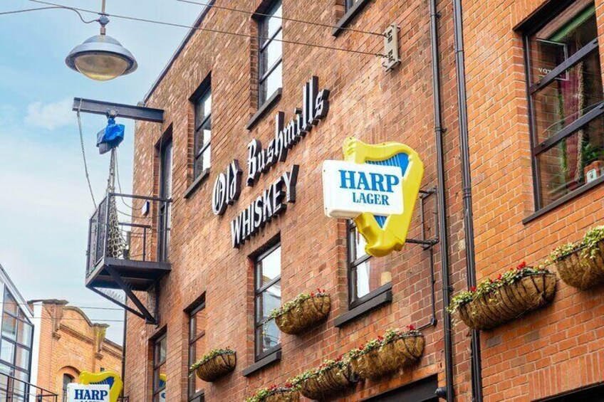 A brick building with signs for Old Bushmills Whiskey and Harp Lager. 3
