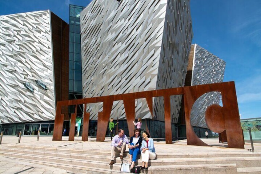 A modern building with a unique angular design and a large metallic sculpture in front. 4