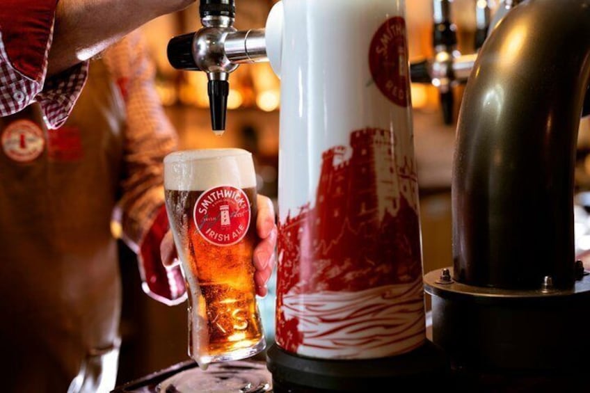 A person pouring beer from a tap into a glass with a label reading 'Swanwick Irish Ale.' 4
