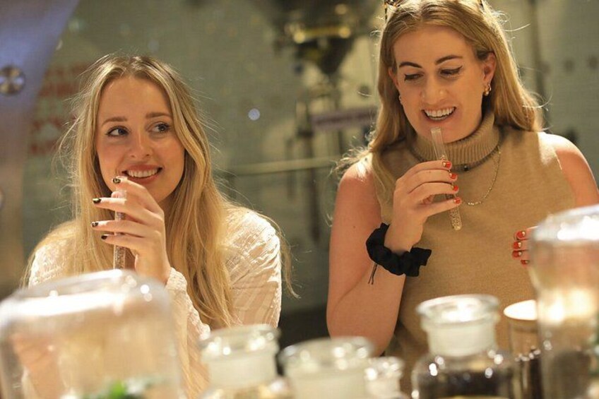 Twee personen zitten aan een tafel met verschillende containers en flessen. 2