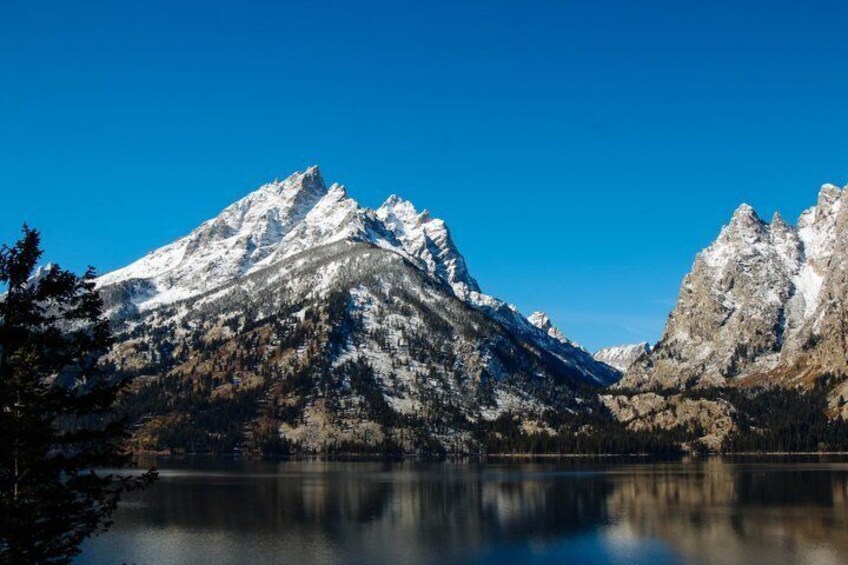 A snow-capped mountain range reflecting in a calm lake. 3