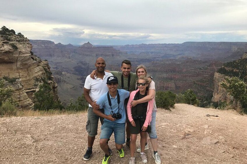 A group of people posing on a rocky outcrop with a canyon in the background. 3