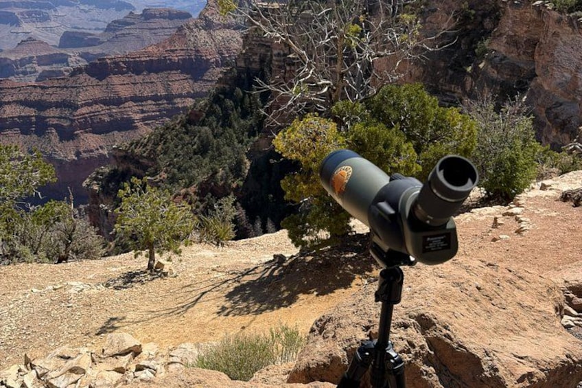 A telescope on a tripod in a desert landscape with rocky terrain and sparse vegetation. 2