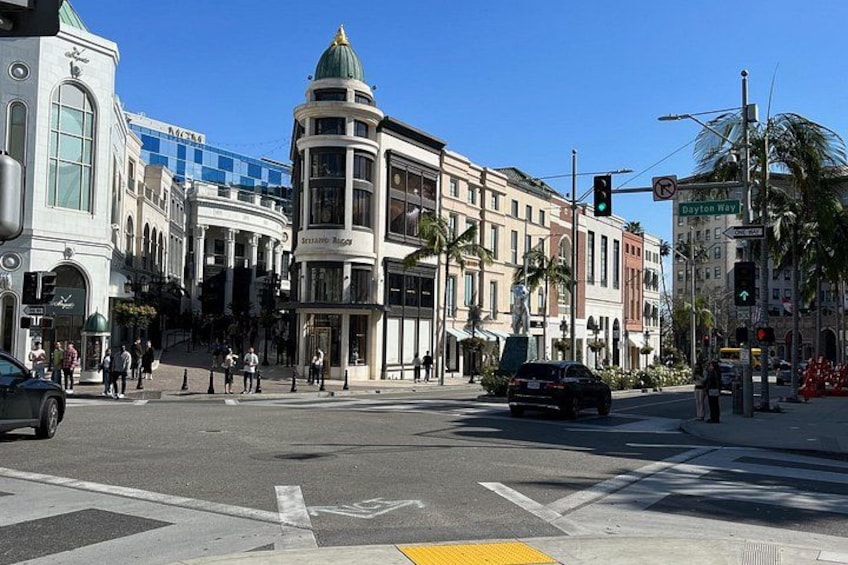 A busy intersection with traffic lights, pedestrians, and historic buildings. 2