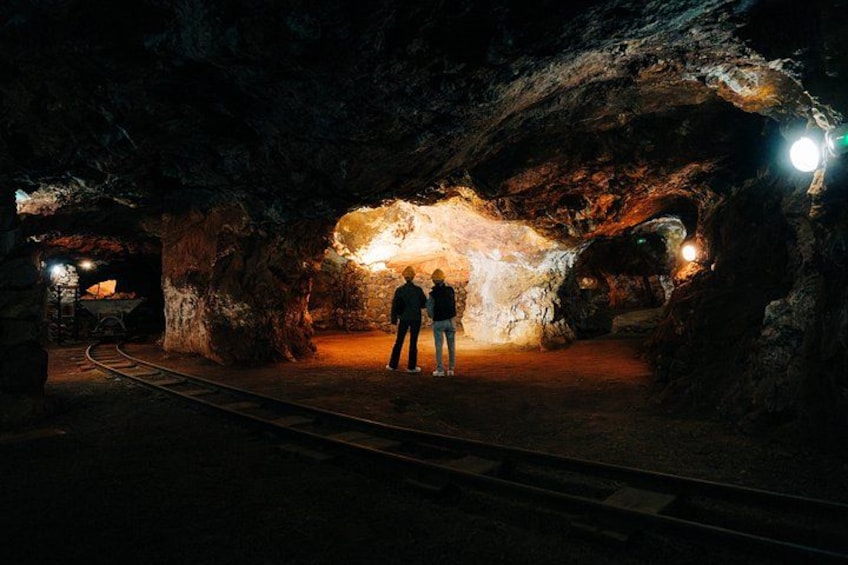 A person standing in a cave with a light source in the background. 5
