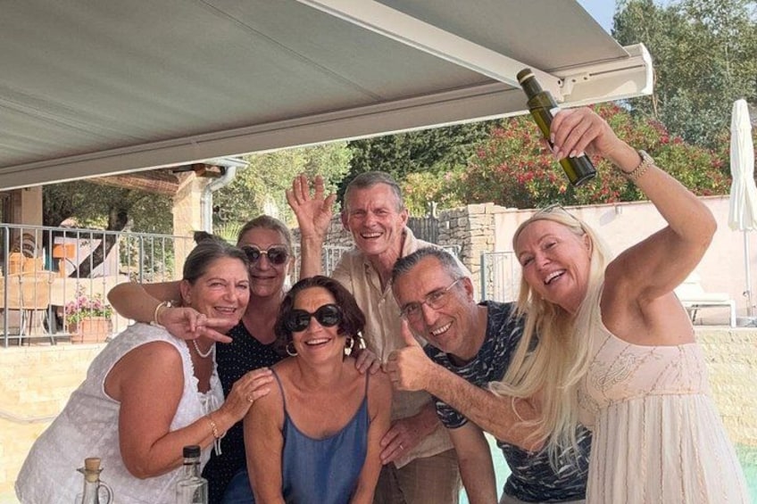A group of people posing under a covered area with a bottle of wine. 4