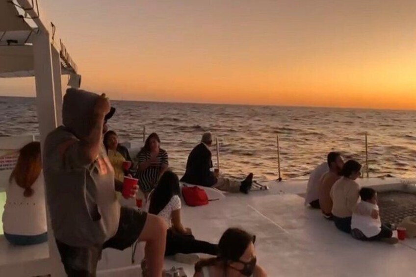 A group of people sitting on a boat deck during sunset. 5