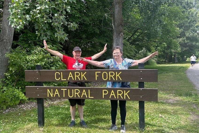 A sign for Clark Fork Natural Park with two people standing beside it. 3