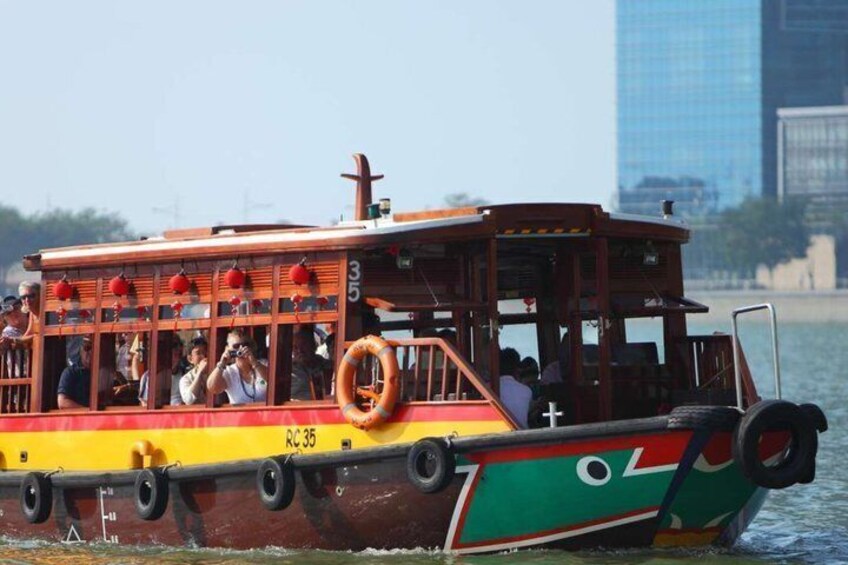 Un bateau coloré transportant des passagers, une bouée de sauvetage et, en arrière-plan, le profil d’une ville. 4