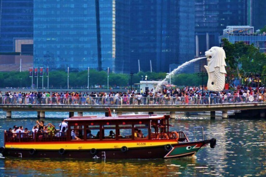Un bateau rempli de touristes, une grande statue blanche et un paysage urbain en arrière-plan. 3