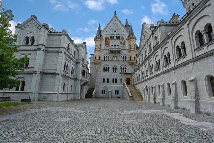 A historic building with a central tower, arched windows, and a cobblestone courtyard. 2