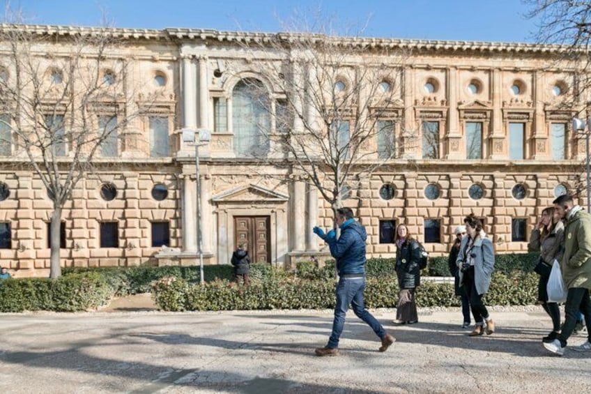 A historic building with classical architecture, a paved plaza, and people walking. 3