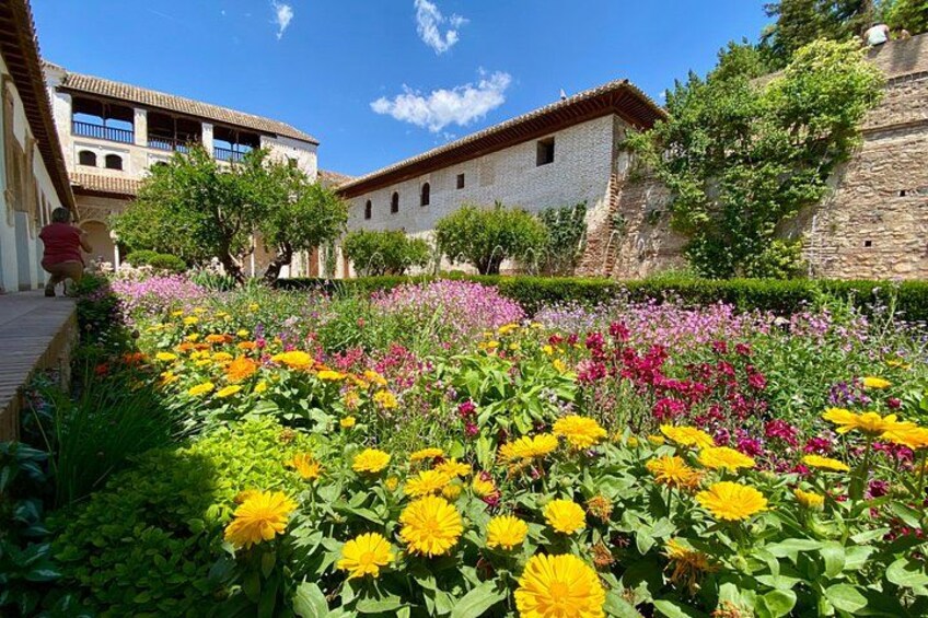 Ein Innenhof mit bunten Blumen, Steingebäuden und blauem Himmel. 5