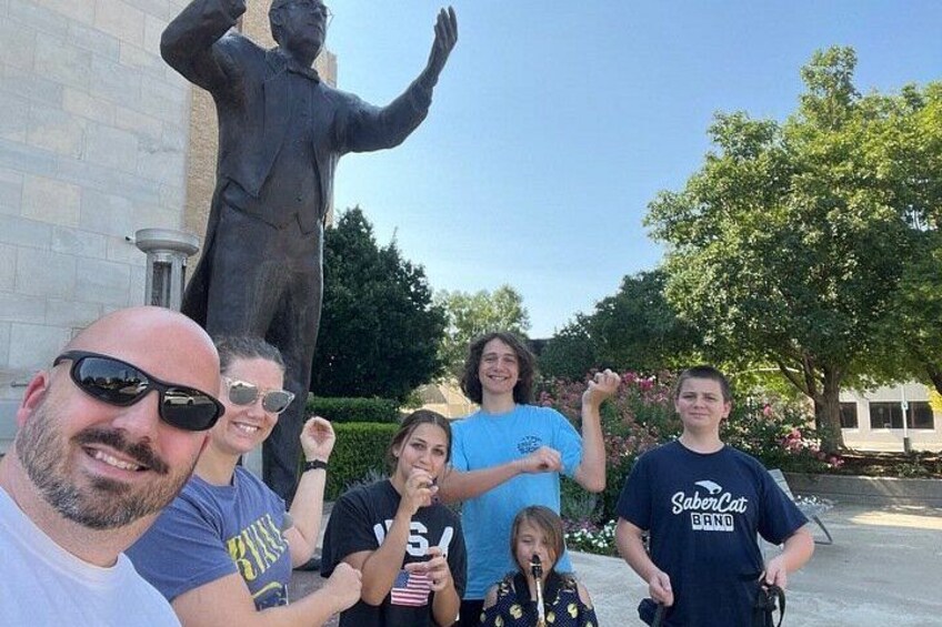 A group of people in front of a statue, with a building in the background. 5
