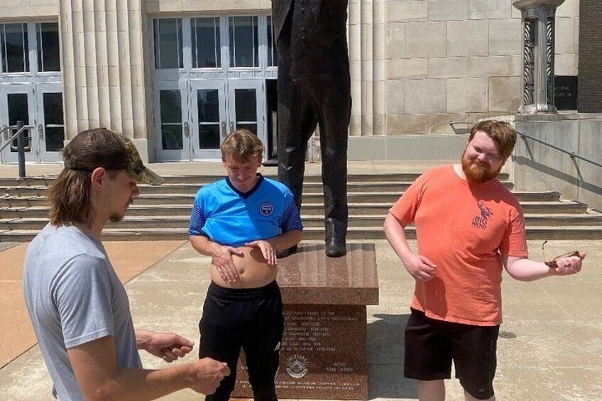 Three people standing near a statue and a plaque. 4