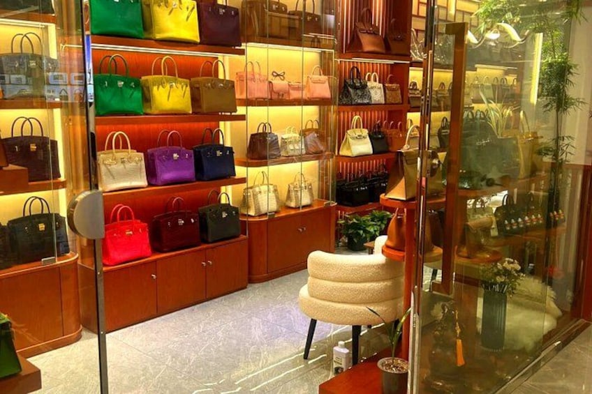 A store interior with shelves of handbags and a stool. 1