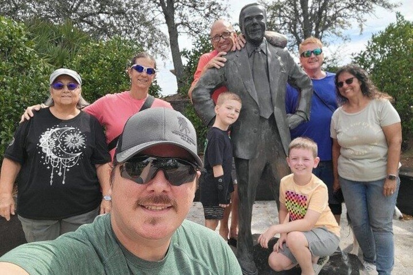 Un grupo de personas posando junto a una estatua. 1
