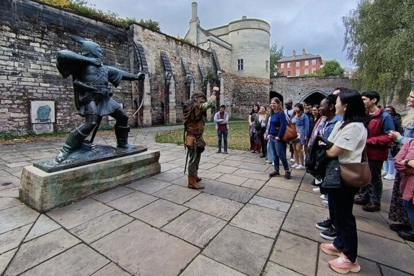 A group of people observing a statue of a knight in armor. 1