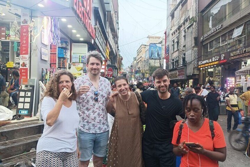A group of people standing on a busy street with shops and signs in the background. 5
