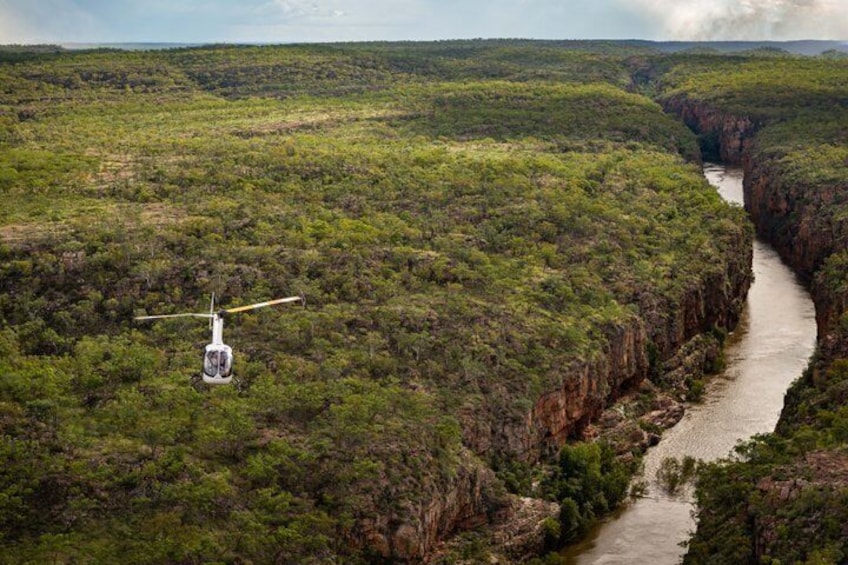 A helicopter flying over a river canyon with dense vegetation. 5