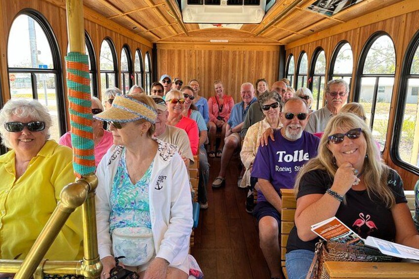 A group of people seated inside a wooden boat with arched windows. 5