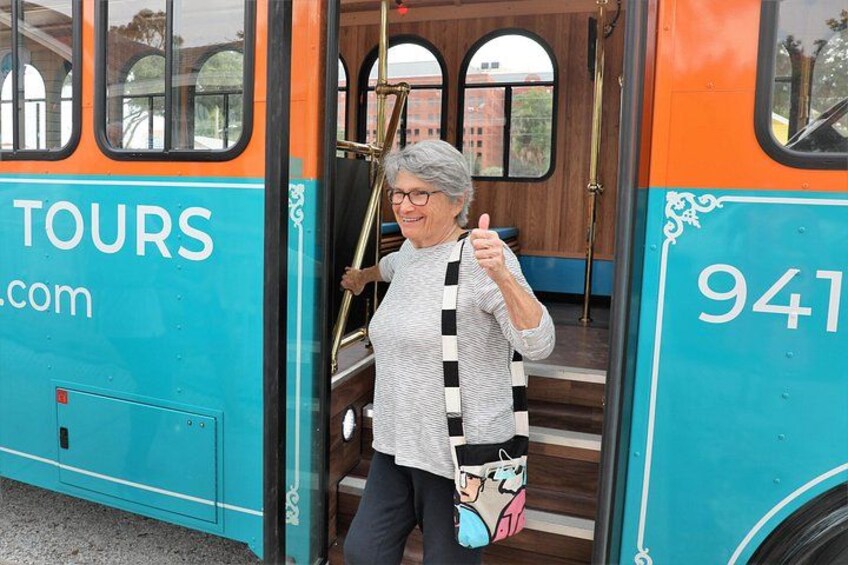 A person exiting a turquoise and orange bus with the number 941 and the word 'TOURS' visible on the side. 2