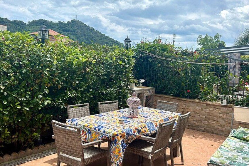 A patio with a table and chairs, surrounded by greenery and a brick wall. 4