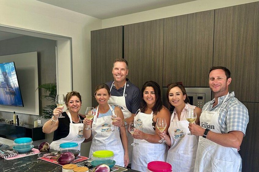 A group of people in a kitchen holding wine glasses. 1
