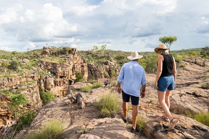 Two people walking on rocky terrain with sparse vegetation and a clear sky. 2