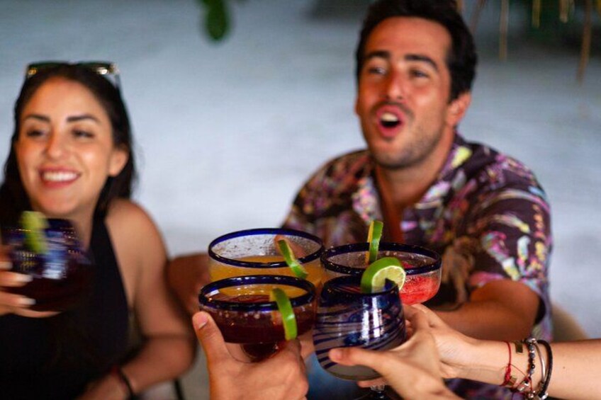 Un gruppo di persone sorseggia cocktail colorati con cannucce e spicchi di lime. 1