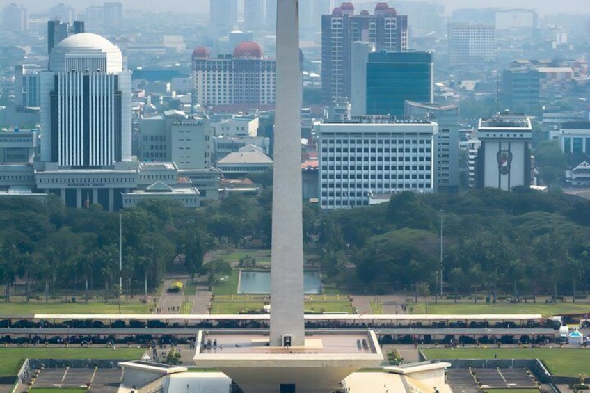 A cityscape with a prominent monument, modern buildings, and a park area. 1