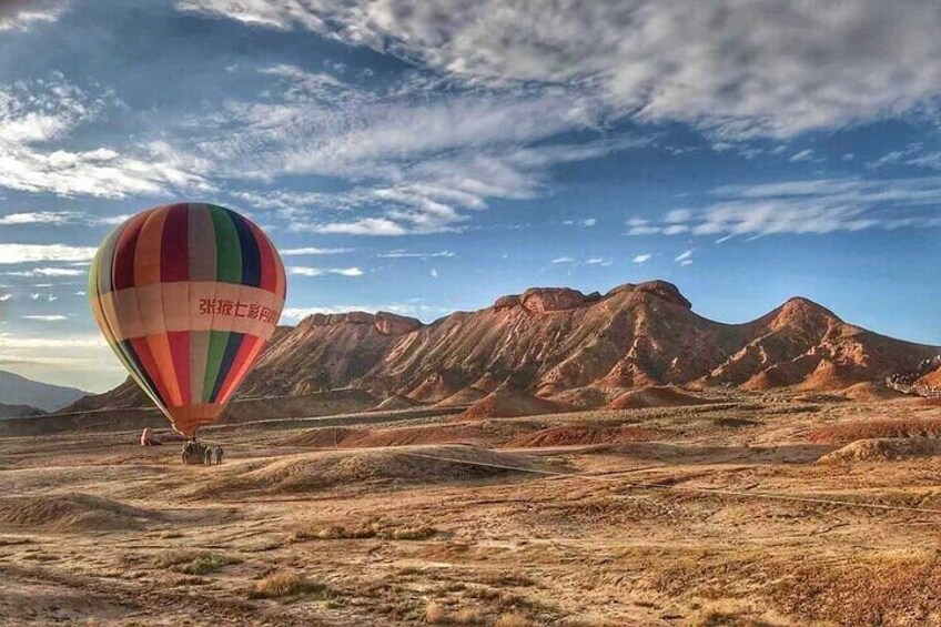A hot air balloon over a desert landscape with mountains in the background. 4
