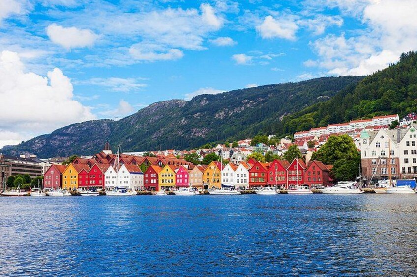 A waterfront town with colorful houses, a river, and mountains in the background. 4